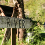 Cartello di legno con la scritta River sul sentiero per il fiume a Coreglia Ligure
